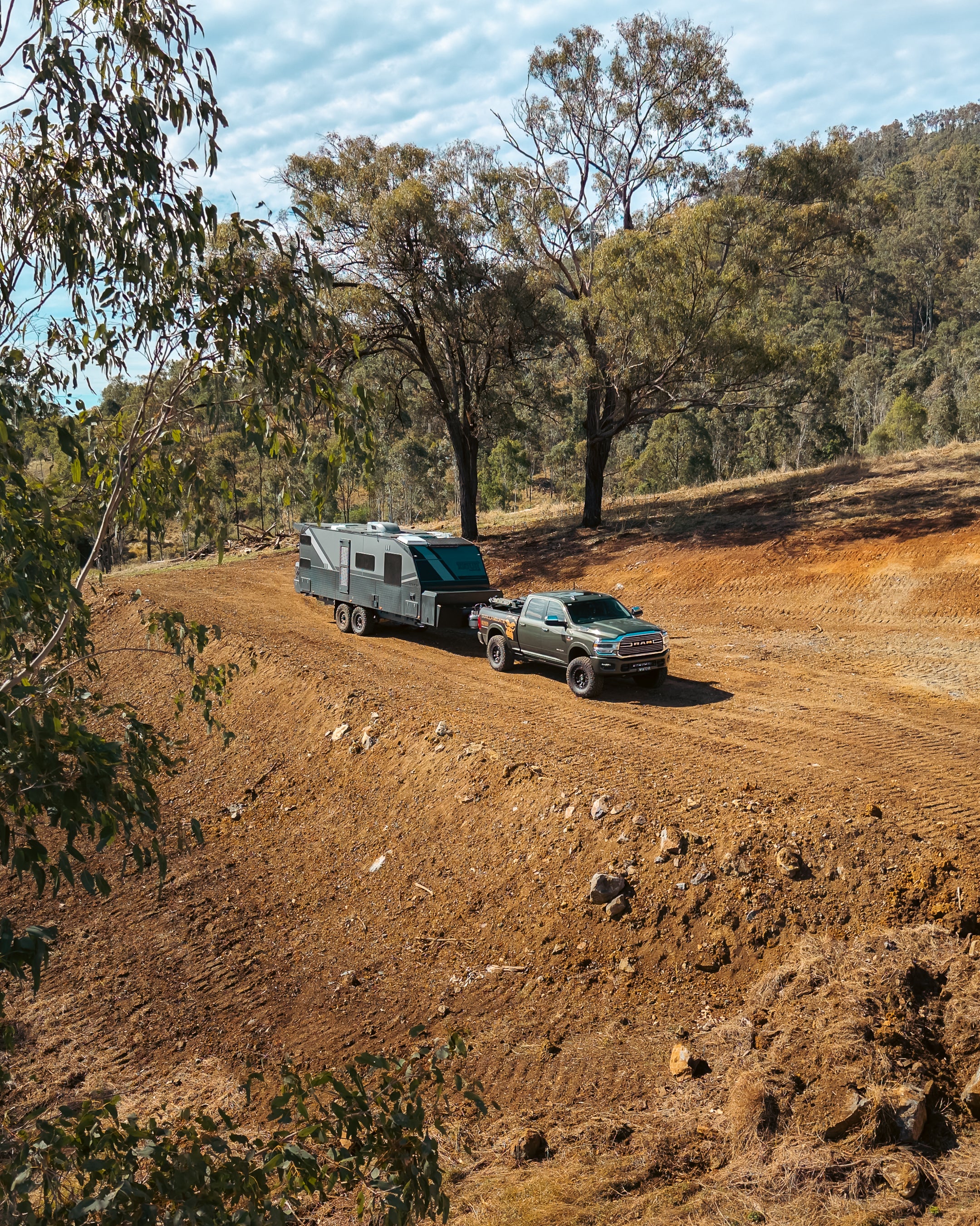 Touring vehicle towing a caravan on a rugged Australian track