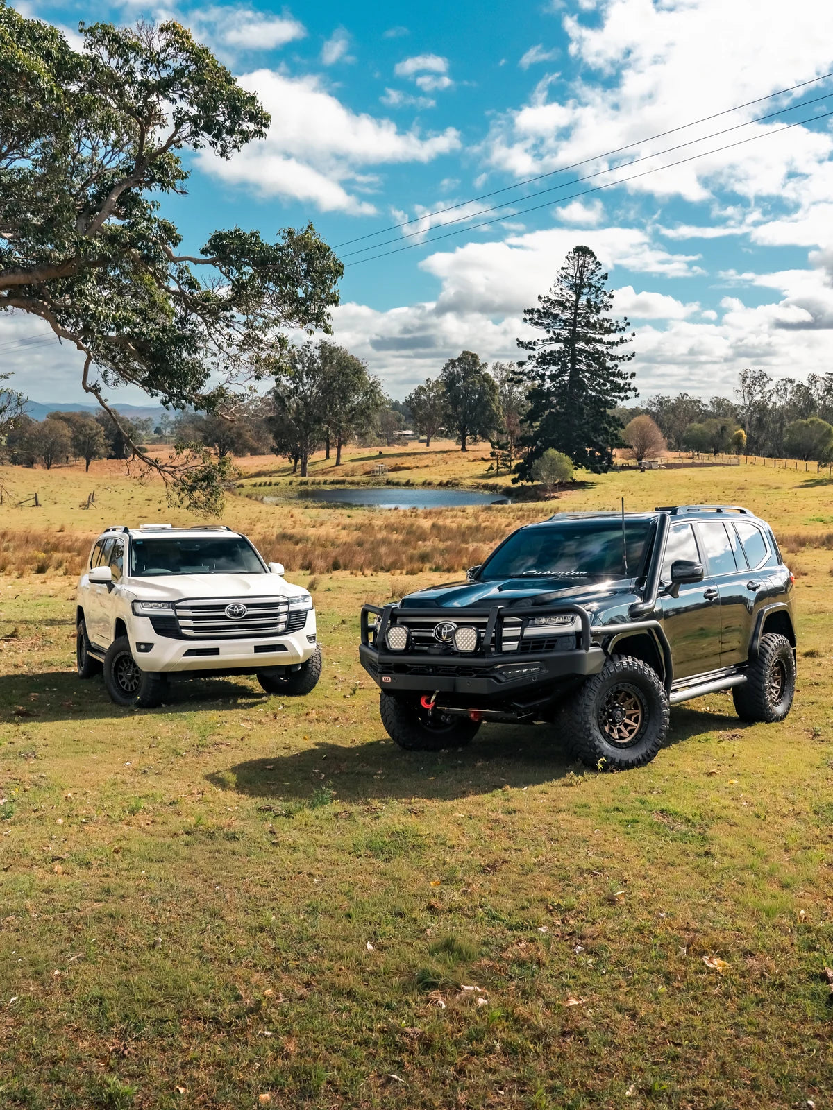 Two Toyota LandCruiser 300 Series wagons set up for touring in an Australian paddock